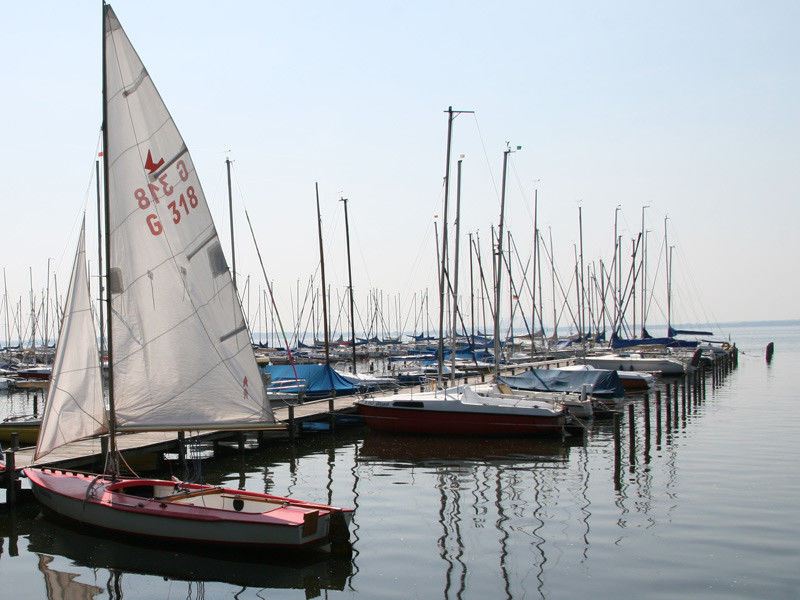 Steg mit Segelbooten, das erste Boot hat gesetzte Segel Steg mit Segelbooten, das erste Boot hat gesetzte Segel