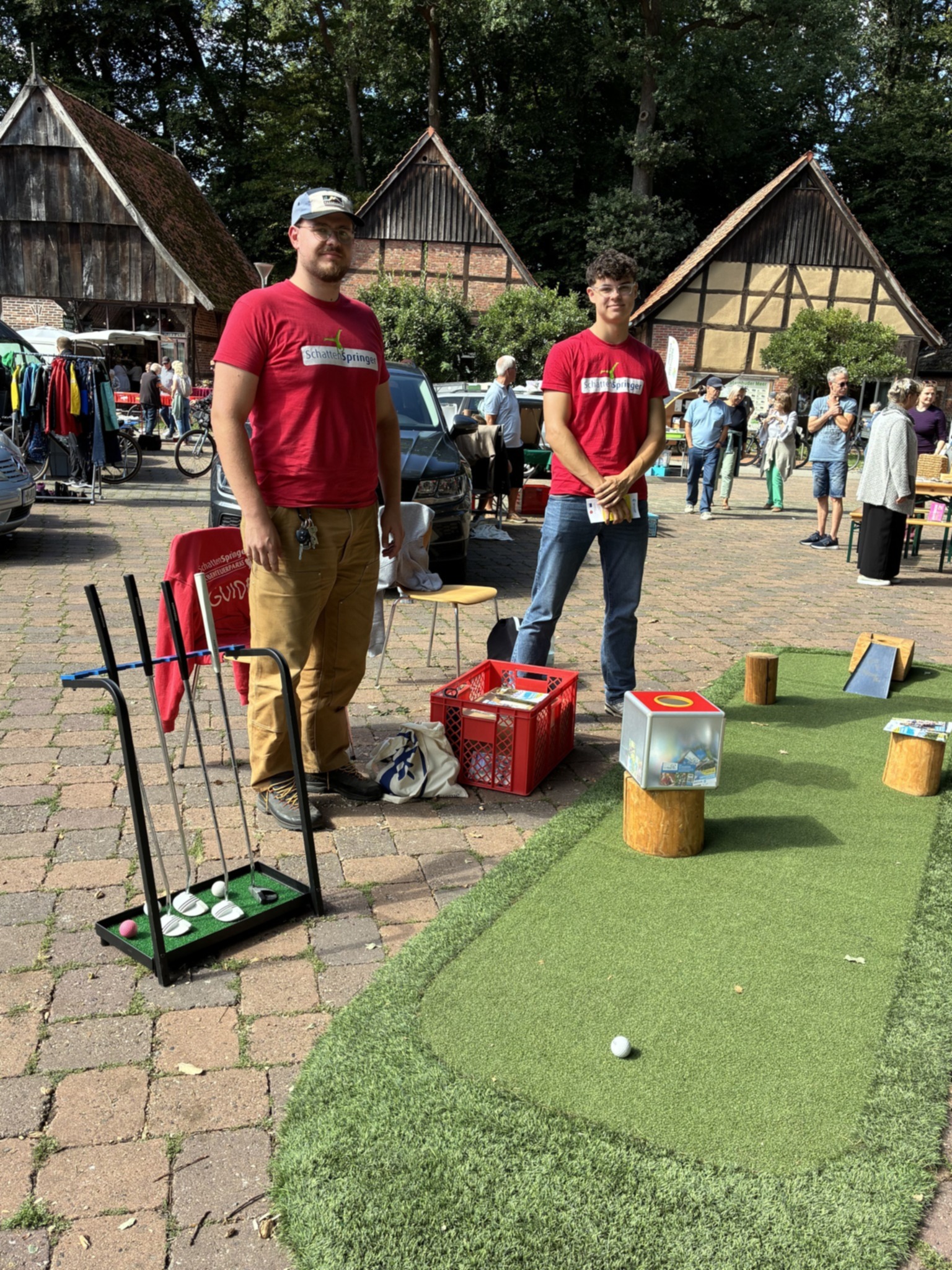 Zwei M&auml;nner stehen an einer mobilen Minigolfanlage