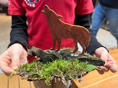 Eine Person hält einen gebastelten Wolf vor der Brust.