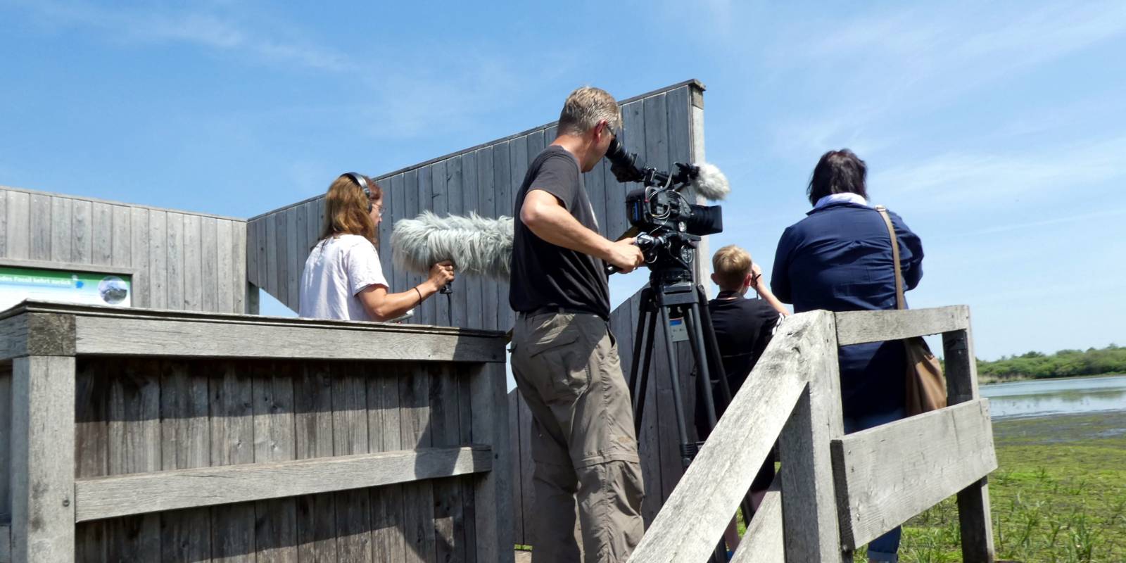 Eine Frau und ein Junge stehen auf einer Aussichtsplattform und schauen auf den Meerbruch im Naturpark Steinhuder Meer. Dahinter steht ein Filmteam und fängt die Szene in Bild und Ton ein.