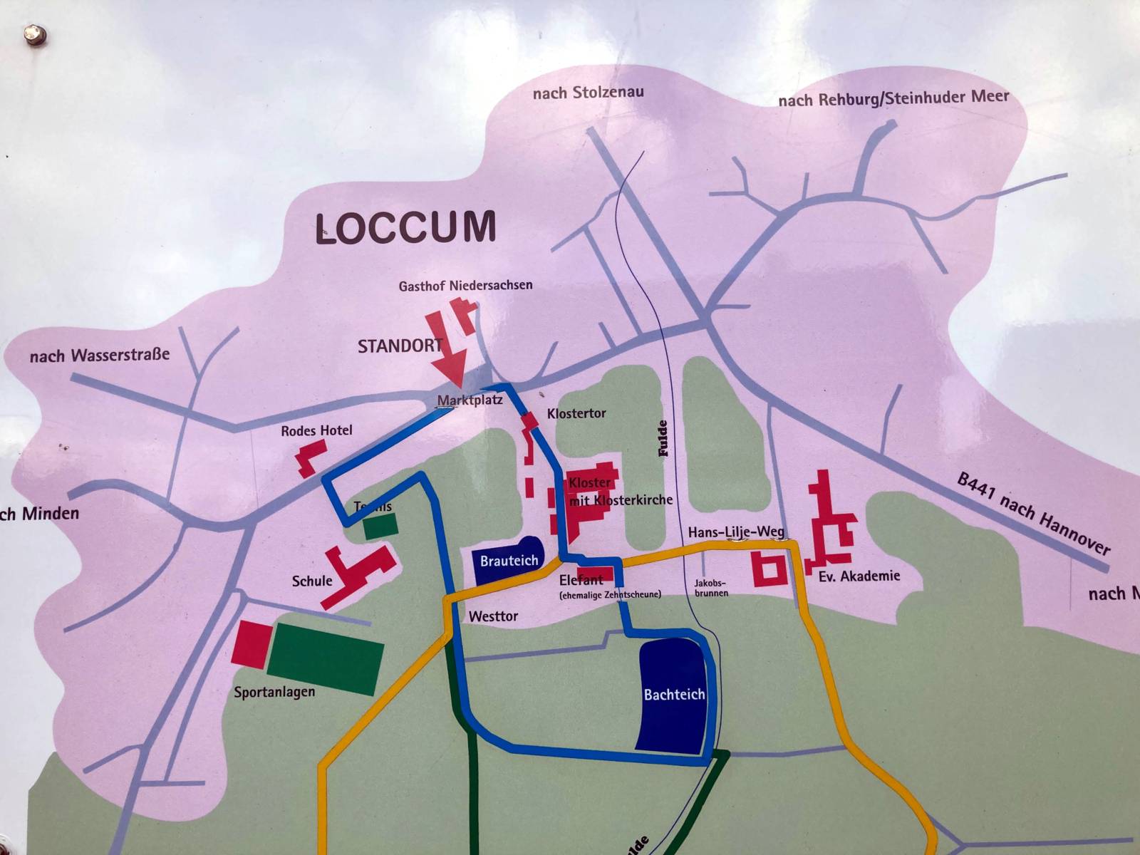 Karte, die am Rand eines Wanderwegs aufgestellt ist. Verschiedene Wege und Gebäude sind gekennzeichnet.