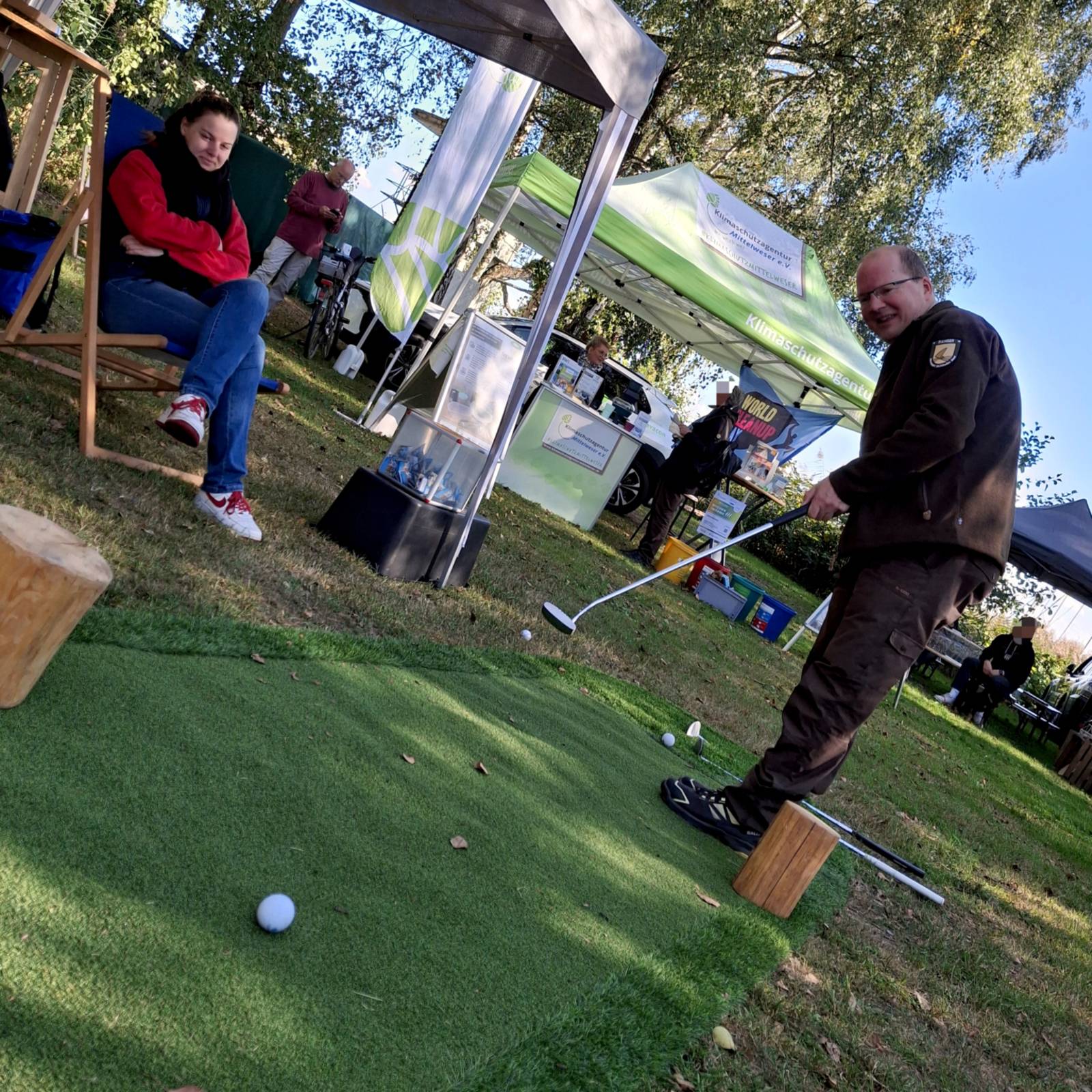 Ein Mann trägt Outdoor-Kleidung und spielt Minigolf.