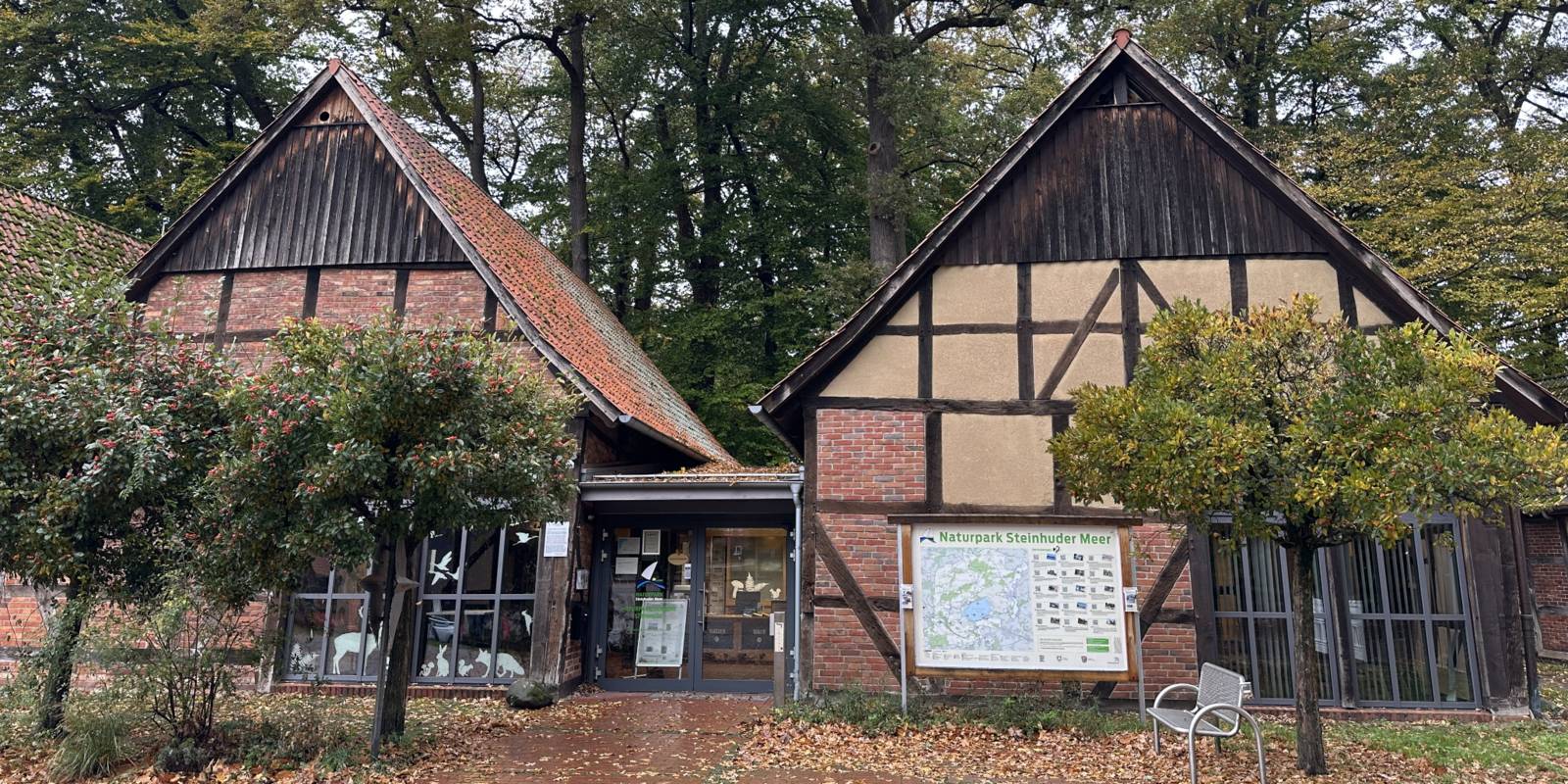Zwei Fachwerkscheunen bilden ein großes Gebäude, Schilder weisen auf das "Infozentrum Steinhude Naturpark Steinhuder Meer" hin.