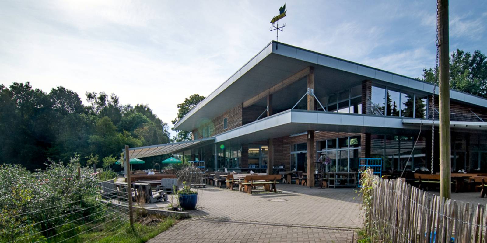 Gebäude mit sichtbarem Holz und Glas und flachem Dach umgeben von Heidelbeersträuchern.