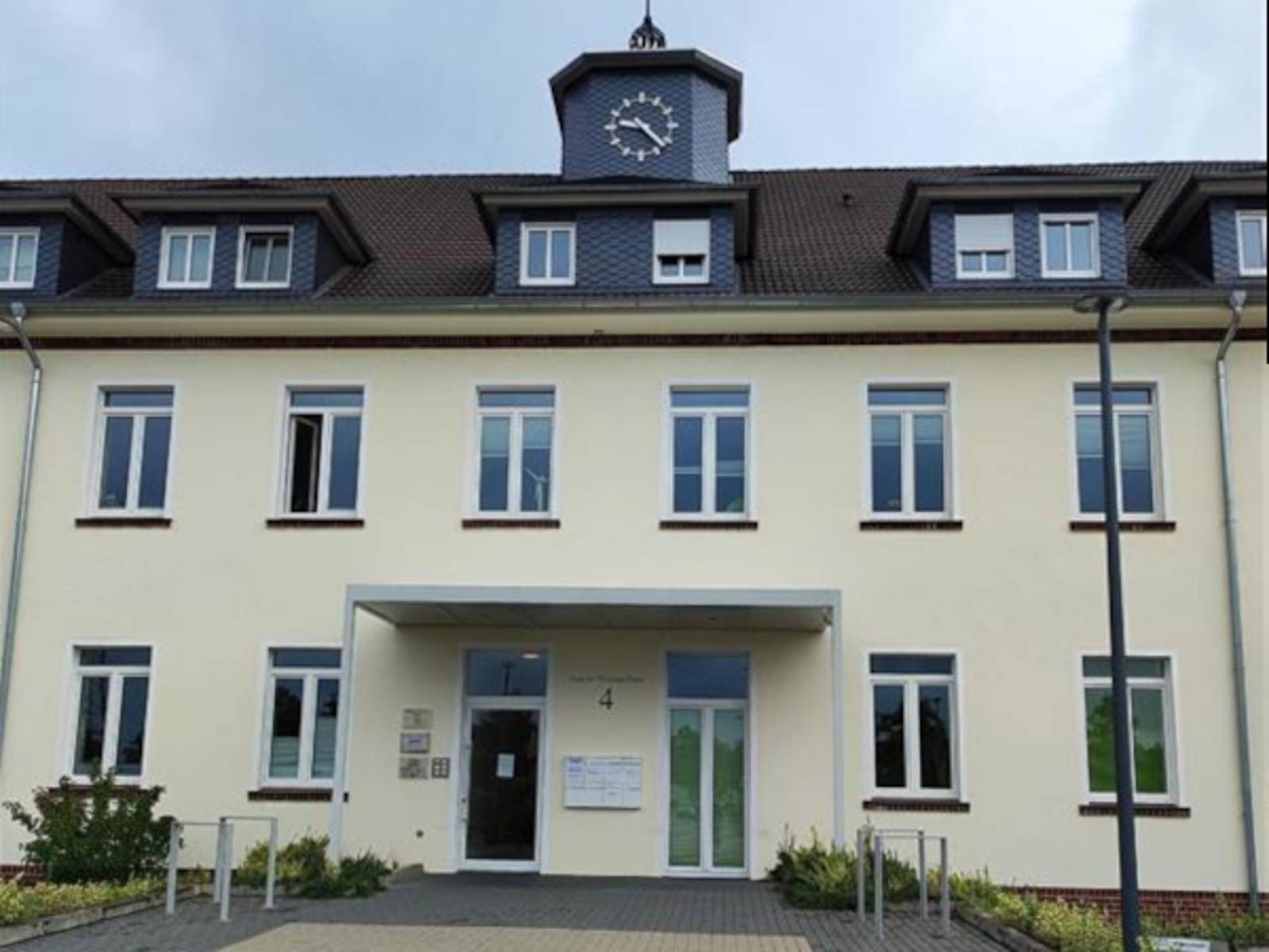 Gebäude mit kleiner Turmuhr und überdachtem Eingang