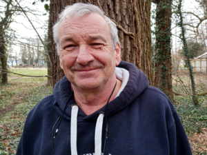 Portraitfoto eines Mannes vor einem Baum.