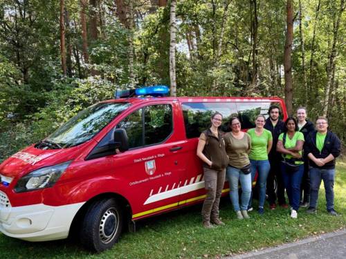 Sieben Personen stehen vor einem Mannschaftstransportfahrzeug der Freiwilligen Feuerwehr
