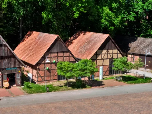 Zwei Fachwerkscheunen bilden ein großes Gebäude, Schilder weisen auf das "Infozentrum Steinhude Naturpark Steinhuder Meer" hin.