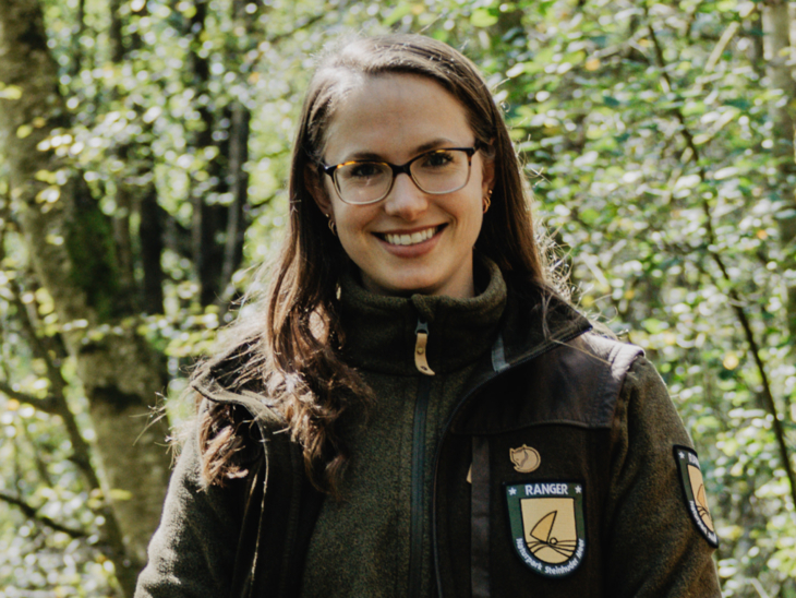 Eine Frau steht draußen am Steinhuder Meer. Sie trägt eine Fleece-Jacke mit der Aufschrift "Naturpark Ranger".