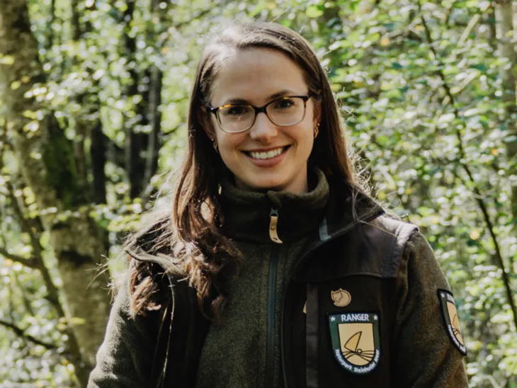 Eine Frau steht draußen am Steinhuder Meer. Sie trägt eine Fleece-Jacke mit der Aufschrift "Naturpark Ranger".