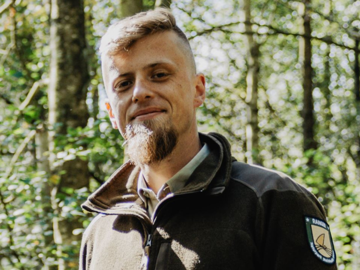 Ein Mann steht draußen am Steinhuder Meer. Er trägt eine Fleece-Jacke mit der Aufschrift "Naturpark Ranger".