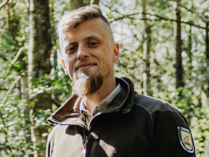 Ein Mann steht draußen am Steinhuder Meer. Er trägt eine Fleece-Jacke mit der Aufschrift "Naturpark Ranger".