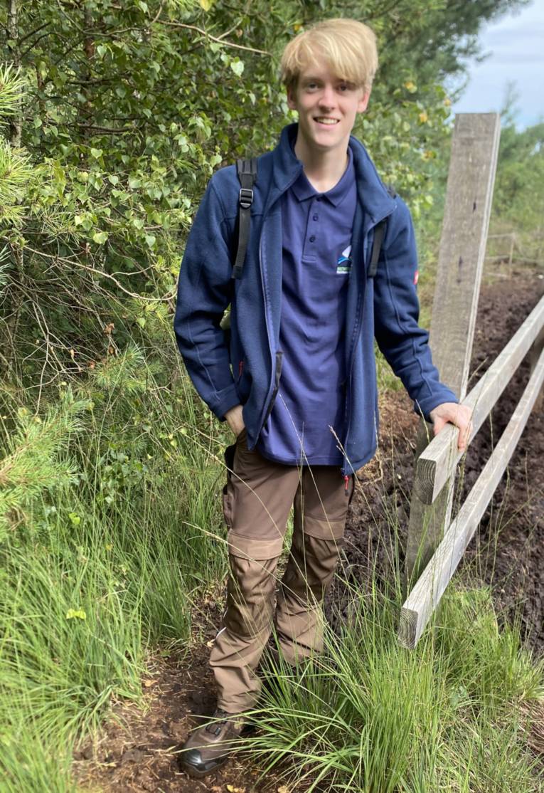 Jemand steht an einem Barfußpfad im Moor.