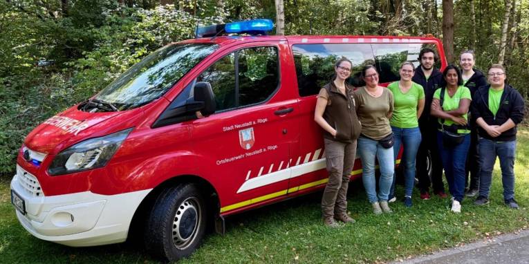 Sieben Personen stehen vor einem Mannschaftstransportfahrzeug der Freiwilligen Feuerwehr