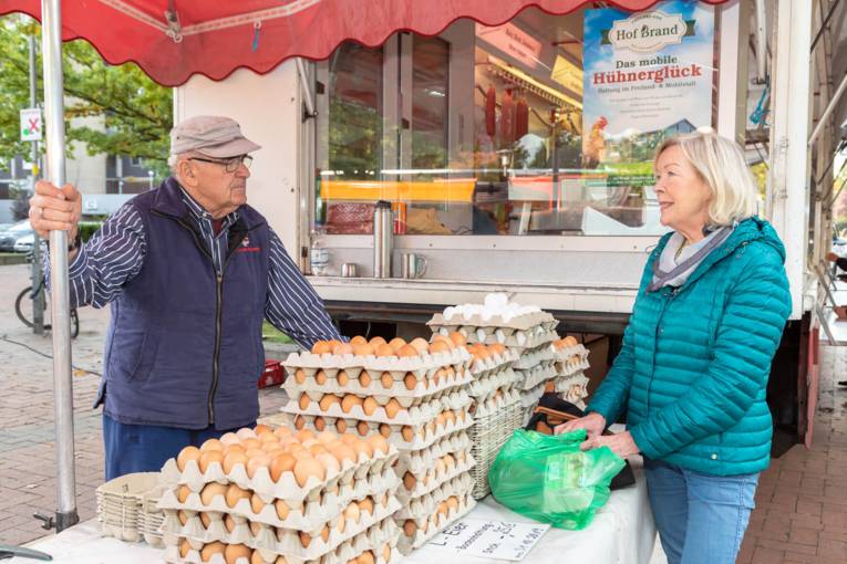 Ein Eierhändler unterhält sich mit einer Kundin.