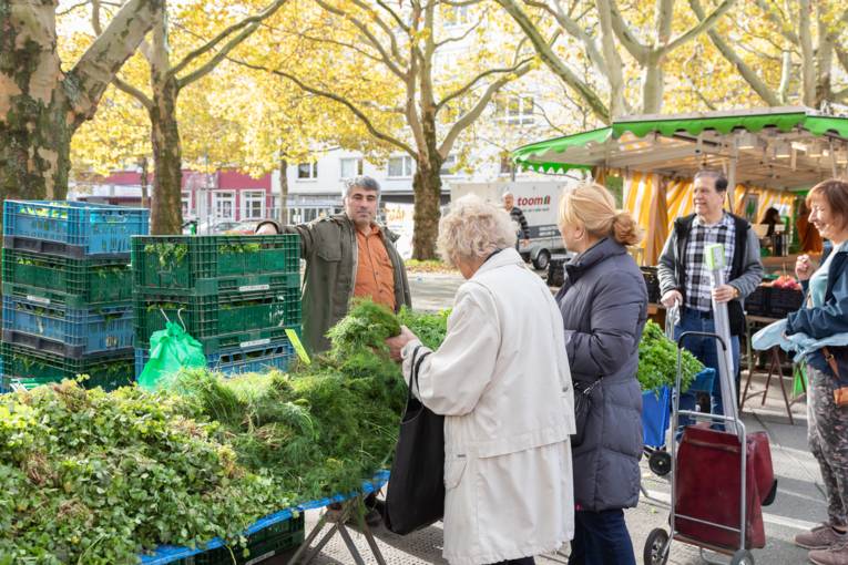 Verkäufer und Kundschaft an einem Marktstand.