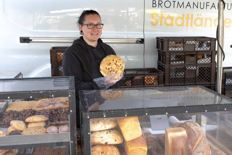 Eine Verkäuferin hält ein frisch gebackenes Brot in die Kamera.