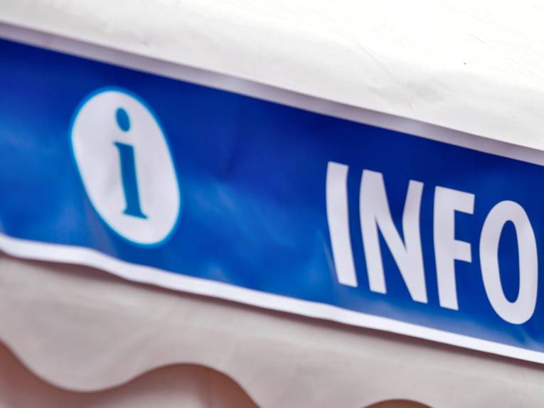 Am Dach eines weißen Zeltes ist ein Banner angebracht. Darauf steht "Info", daneben ist das "i" für Information.