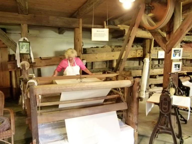 Eine Frau arbeitet an einer historischen Kastenmangel