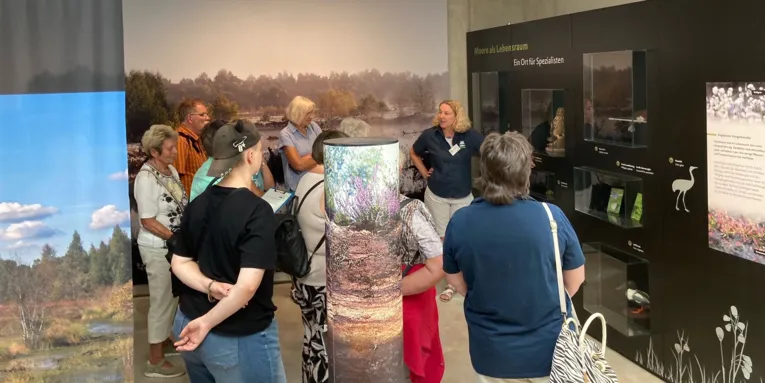 Menschen werden durch eine Ausstellung gef&uuml;hrt.
