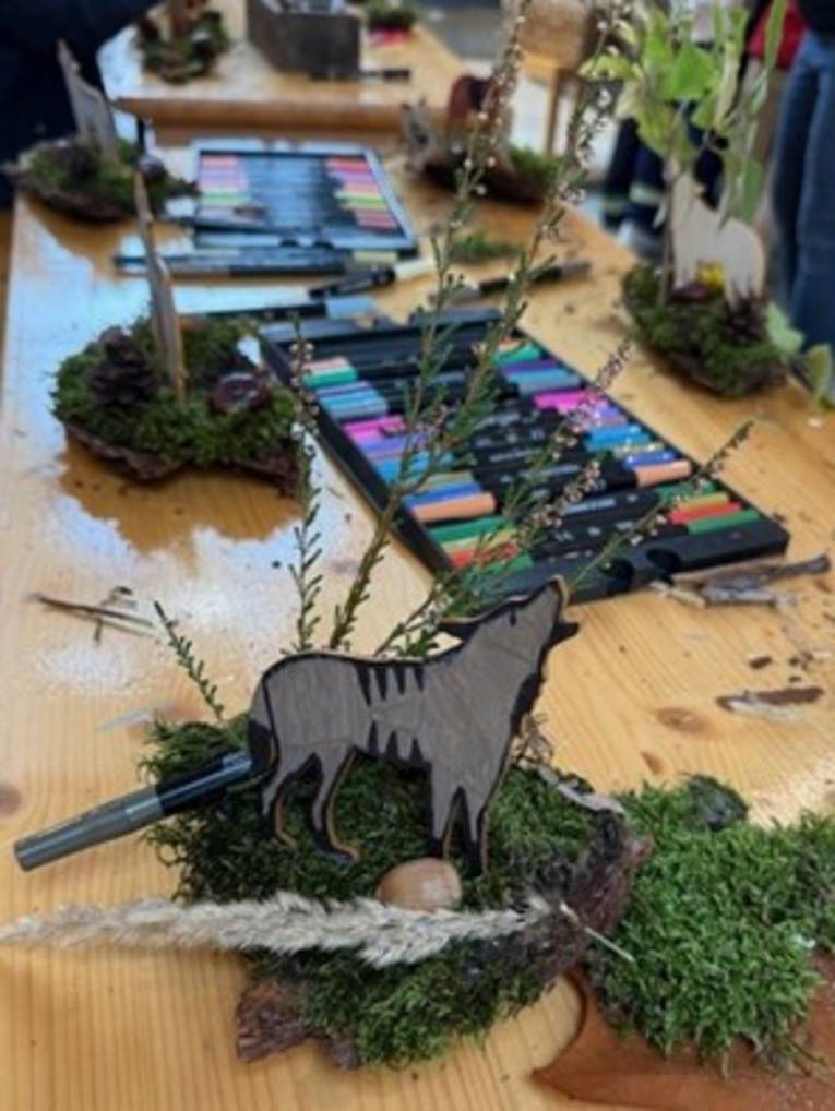 Eine Person hält einen gebastelten Wolf vor der Brust.