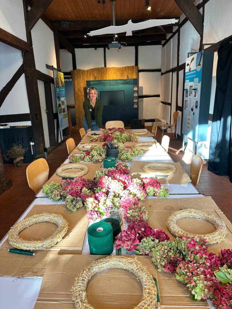 Tisch mit Strohkränzen und Bastelmaterial