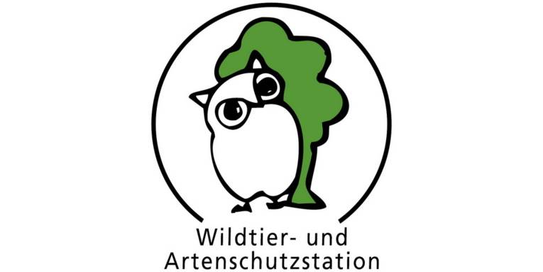 Logo: Eine mit wenigen Strichen gezeichnete Eule steht vor einem gezeichneten Baum. Ein nach unten offener Kreisbogen umschließt die Zeichnungen. In der Öffnung unten steht: "Wildtier- und Artenschutzstation".