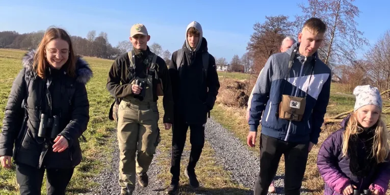 Sechs Personen gehen auf einem Feldweg.