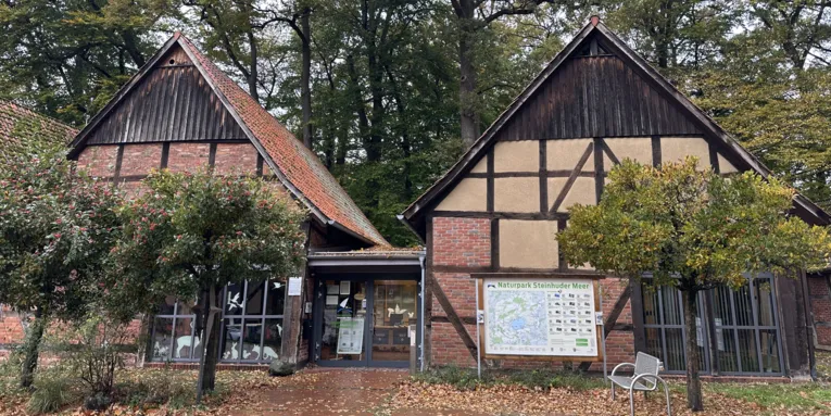 Zwei Fachwerkscheunen bilden ein gro&szlig;es Geb&auml;ude, Schilder weisen auf das "Infozentrum Steinhude Naturpark Steinhuder Meer" hin.