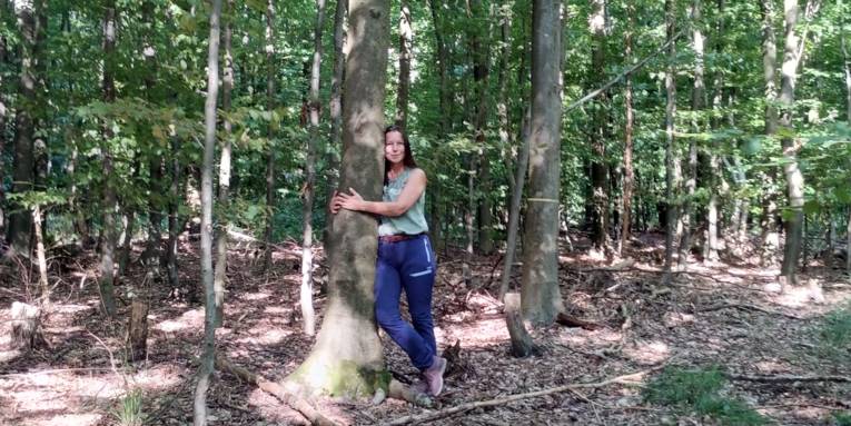 Eine Frau umarmt einen Baum.