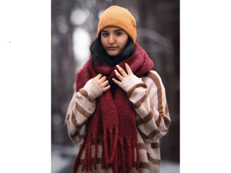 Eine Frau mit Strickpulli, dickem Wollschal und Strickmütze