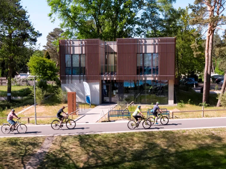 Radfahrerinnen und Radfahrer fahren auf dem Steinhuder Meer Rundweg und kommen direkt am Naturpark-Haus in Mardorf vorbei.