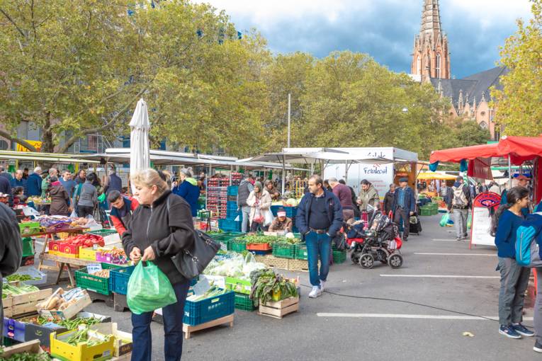 Kundschaft läuft auf dem Wochenmarkt Mitte.