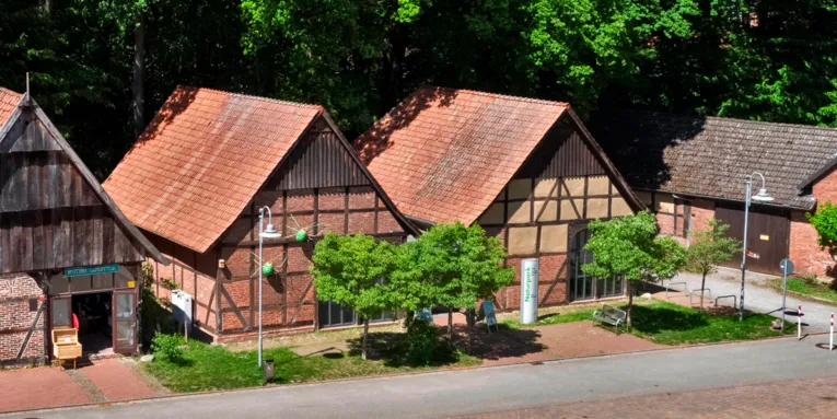 Zwei Fachwerkscheunen bilden ein großes Gebäude, Schilder weisen auf das "Infozentrum Steinhude Naturpark Steinhuder Meer" hin.