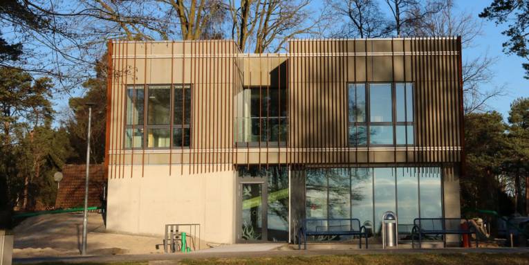 Modernes Gebäude mit flachem Dach und einer Fassade mit Metallstreben.