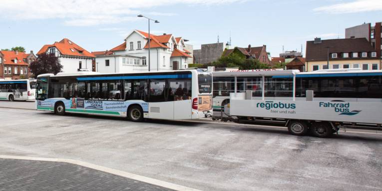 Hinter einem Linienbus hängt ein Anhänger.