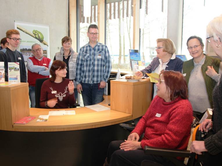 Männer und Frauen versammeln sich um einen Informationstresen.