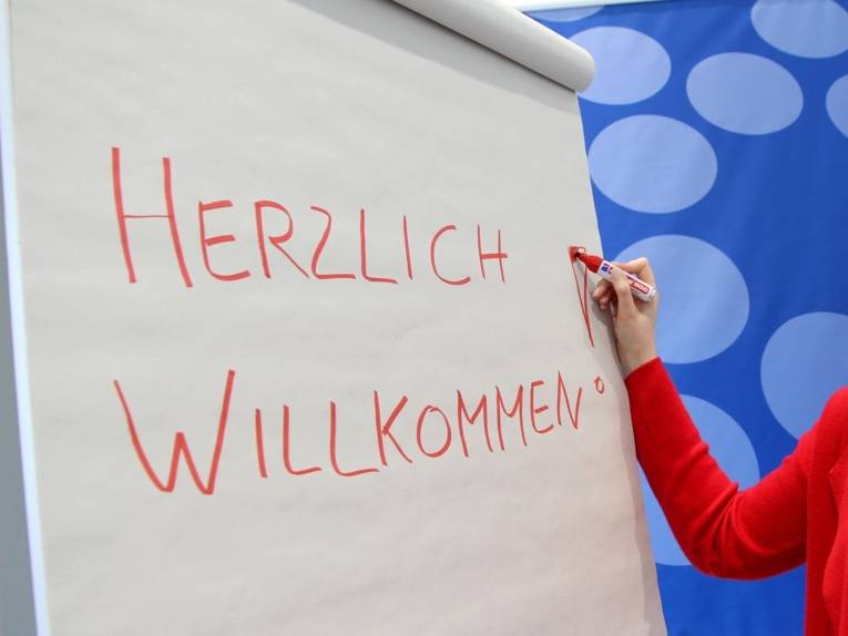 Auf ein Flipchart wird "Herzlich willkommen geschrieben"