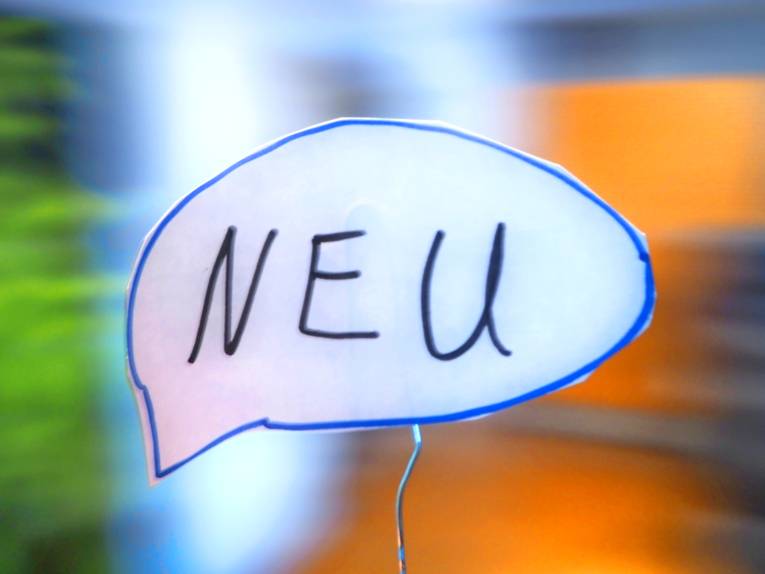 In einer Sprechblase steht "NEU", der Hintergrund ist unscharf.