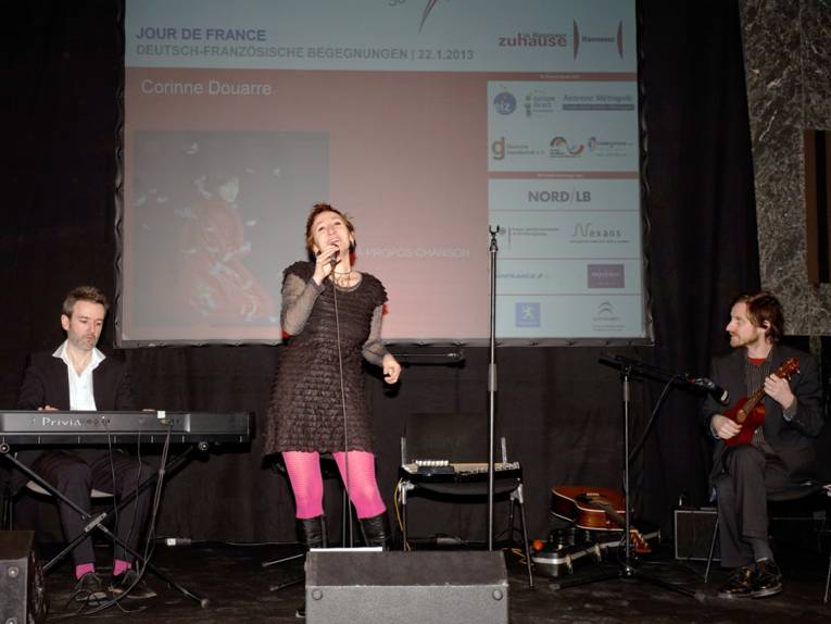 Corinne Douarre, ein Keyboard und ein Gitarrist auf der Bühne