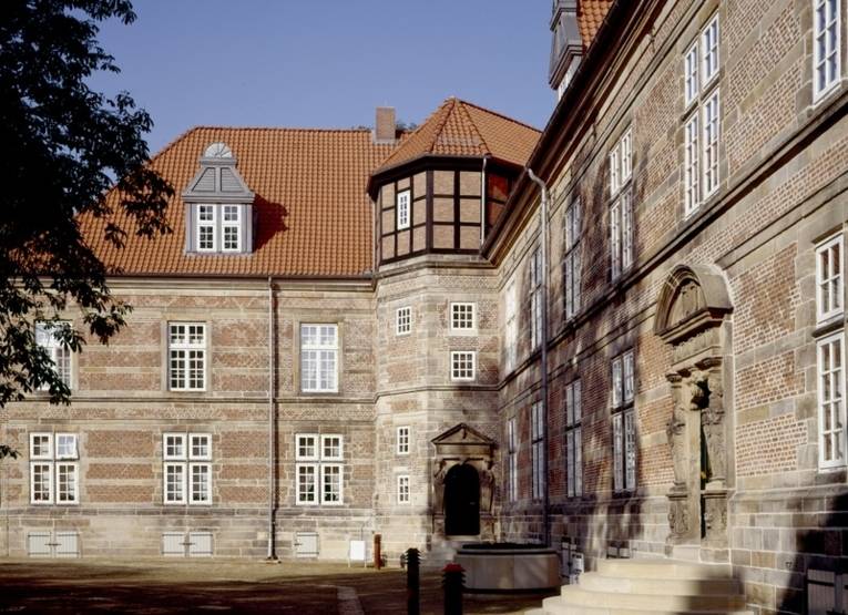 Auf dem Gelände des Neustädter Schloss Landestrost: Ein Teil des Gebäudes, der Eingangsbereich mit Treppe und links im Bild ein Teil einer Baumkrone sind zu sehen.