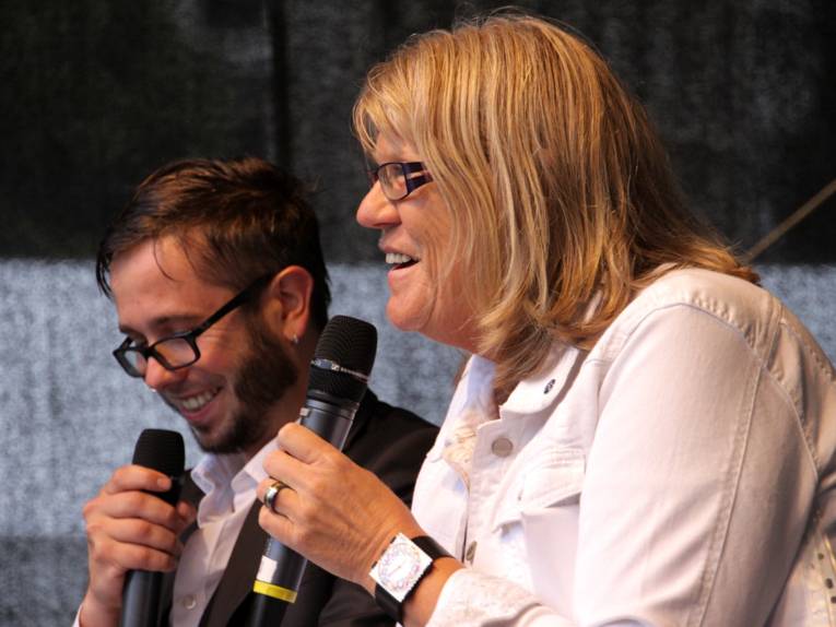 Moderator Jan Egge Sedelies und stellvertretende Regionspräsidentin Angelika Walther vergeben einen der Gewinne bei der Entdeckertagsverlosung.