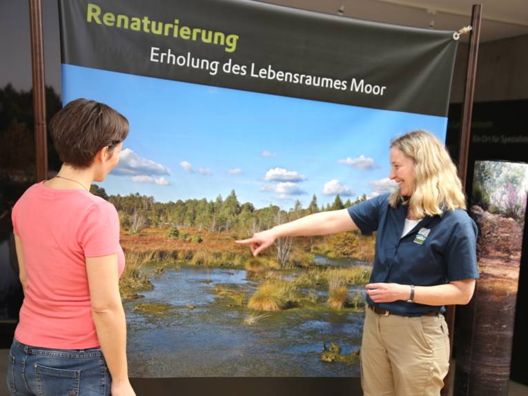 Zwei Frauen betrachten das Bild einer Moorlandschaft.