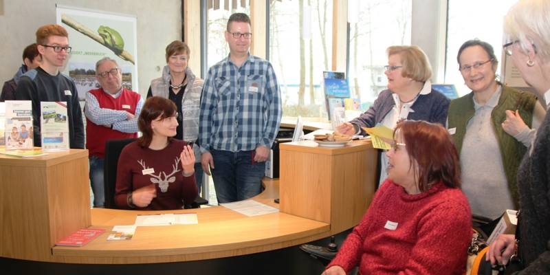 Männer und Frauen versammeln sich um einen Informationstresen.