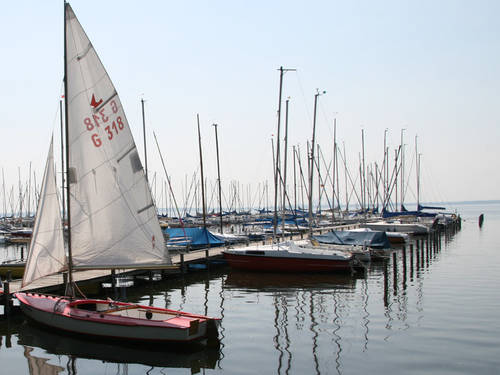Steg mit Segelbooten, das erste Boot hat gesetzte Segel Steg mit Segelbooten, das erste Boot hat gesetzte Segel