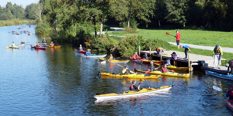 Menschen fahren mit Kanus im Hagenburger Kanal, ihr Ziel scheint eine Anlegestelle zu sein. Menschen fahren mit Kanus im Hagenburger Kanal, ihr Ziel scheint eine Anlegestelle zu sein.