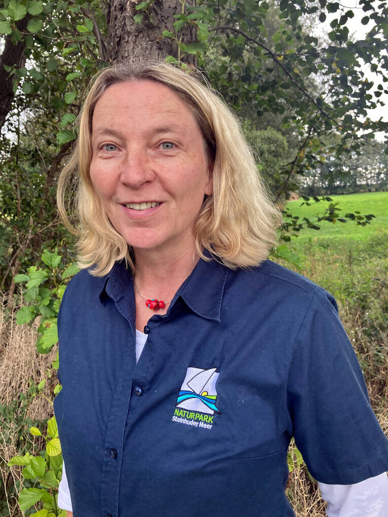 Porträtfoto einer Frau in einem blauen Poloshirt mit Naturparklogo. Porträtfoto einer Frau in einem blauen Poloshirt mit Naturparklogo.